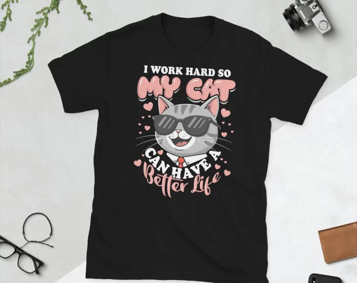 Black I Work Hard for My Cat T-Shirt Flat Lay Flat lay of black "I Work Hard So My Cat Has a Better Life" t-shirt with props on white surface