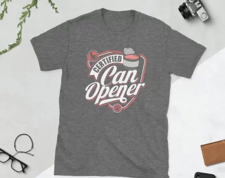 Certified Can Opener Shirt Flat Lay Graphite Heather Flat lay of Graphite Heather Certified Can Opener tee with plant and scissors on white background