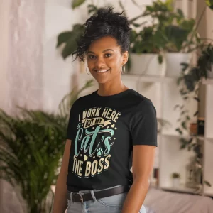 Woman wearing "My Cat’s the Boss" tee with relaxed hairstyle and indoor plants behind.