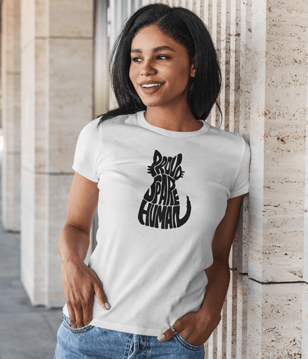 Smiling woman standing by a pillar wearing a white “Proud Spare Human” t-shirt with a black cat silhouette design from Spare Human Society.